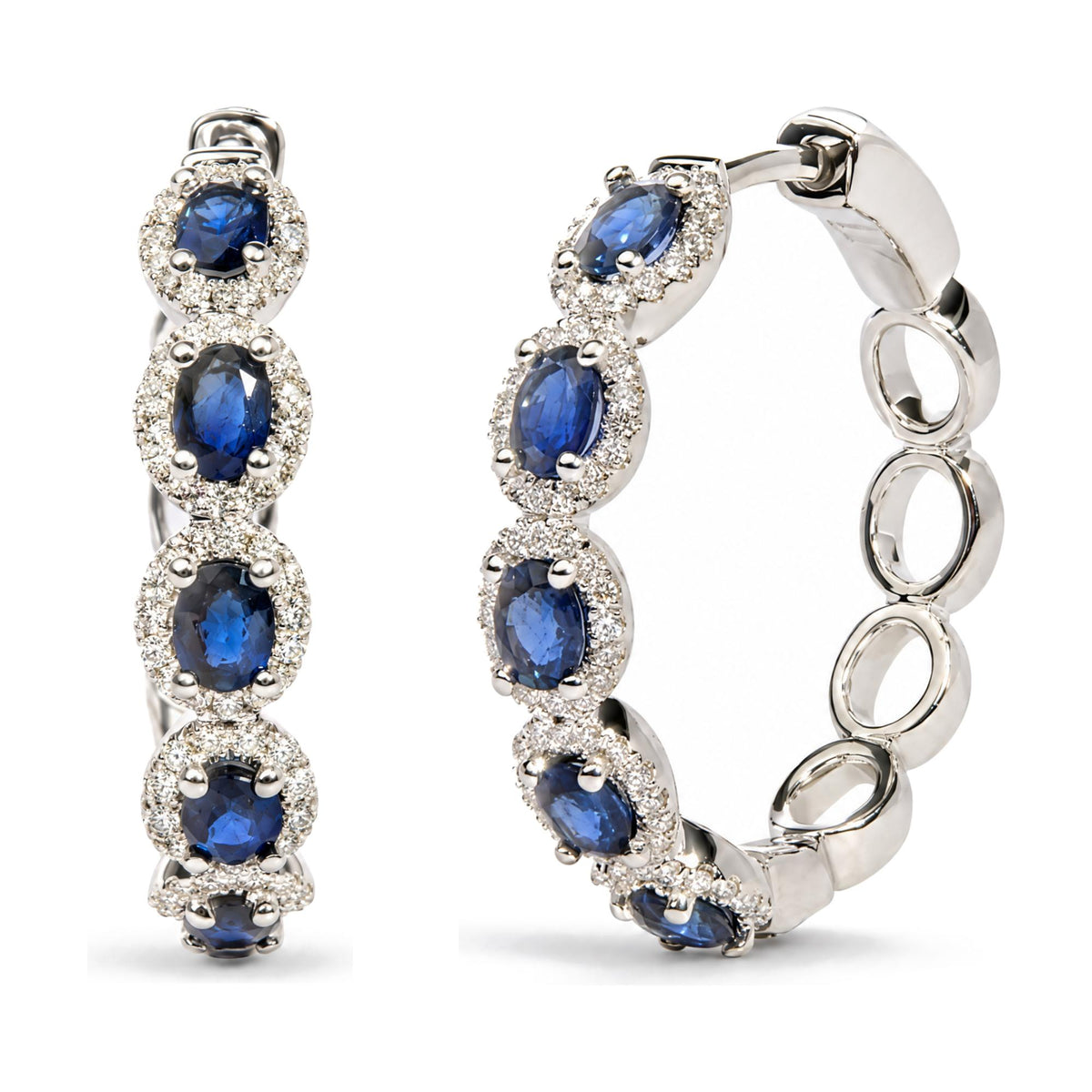 Close-up front and side views of white metal hoop earrings featuring oval blue gemstones surrounded by clusters of small round white gemstones in prong settings.