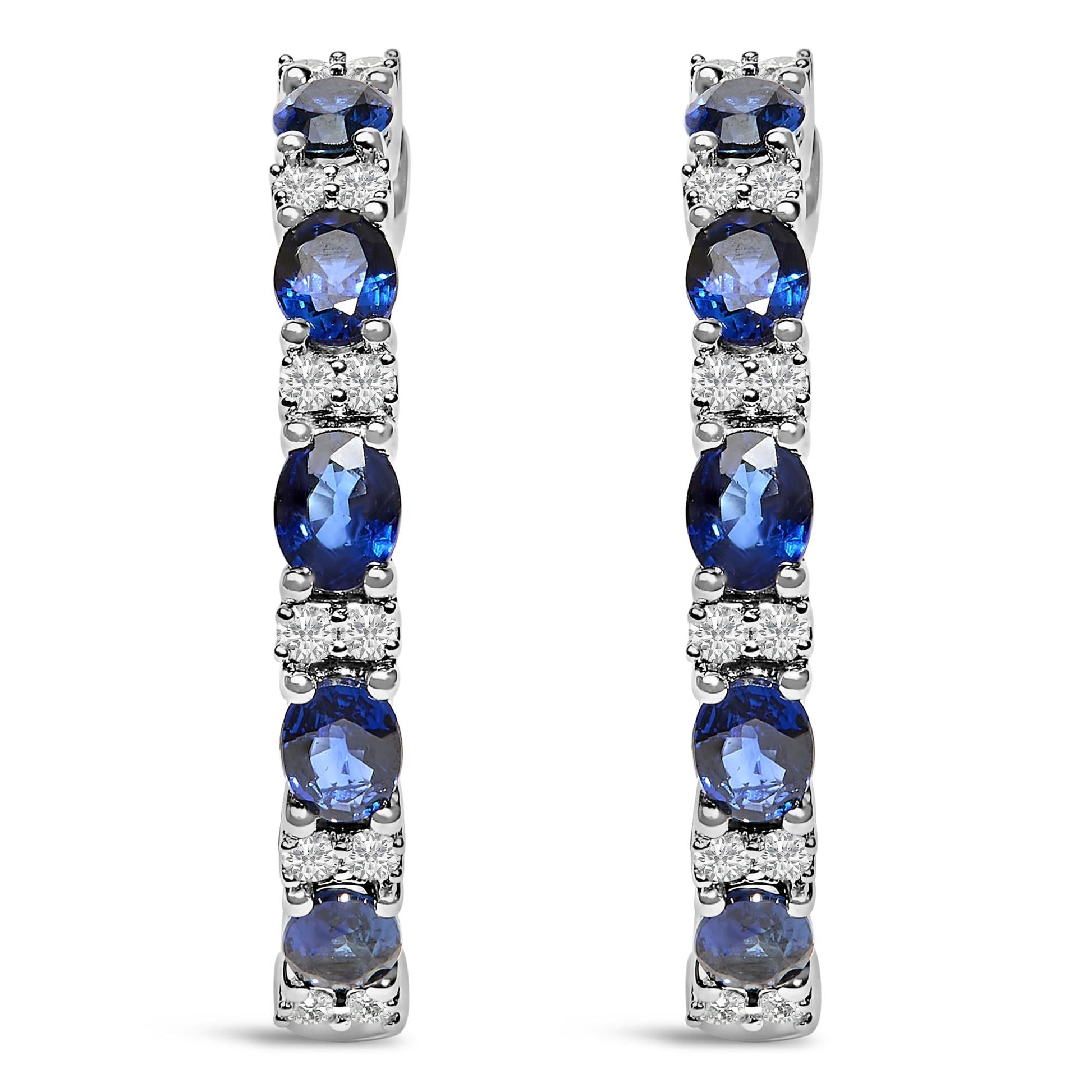 Front view of pair of white metal earrings featuring alternating oval blue gemstones and round white gemstones in shared prong and 4-prong settings.