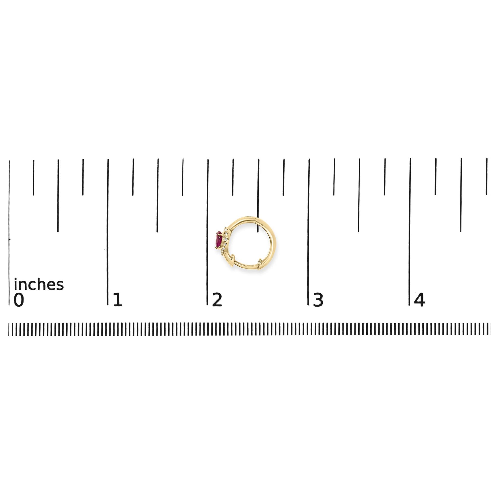 Yellow metal circular earring with red pear-shaped gemstone and small white round gemstones, shown on a ruler scale from above.