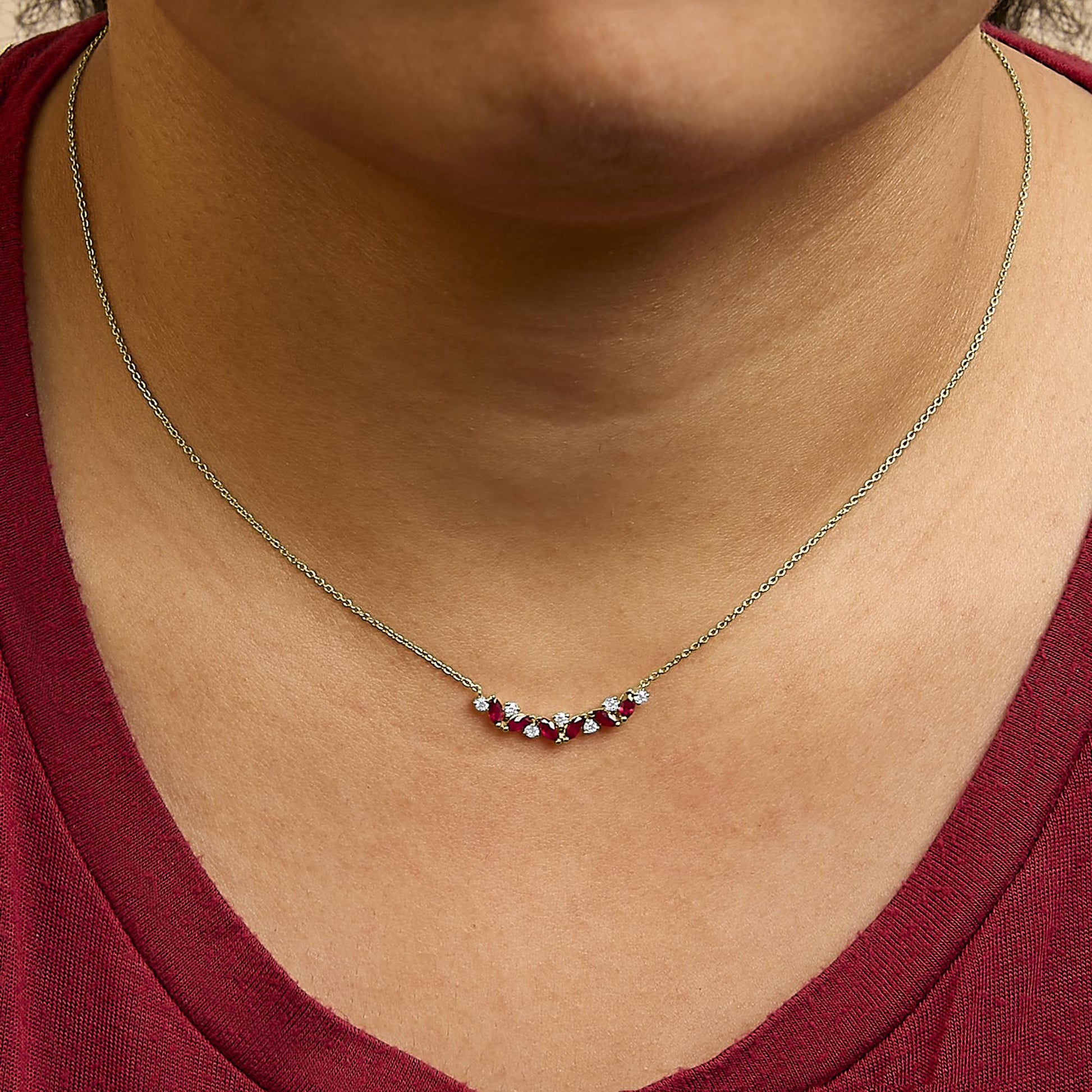 Close-up front view of yellow necklace with alternating red marquise-shaped gemstones and white round gemstones shown worn on a model.