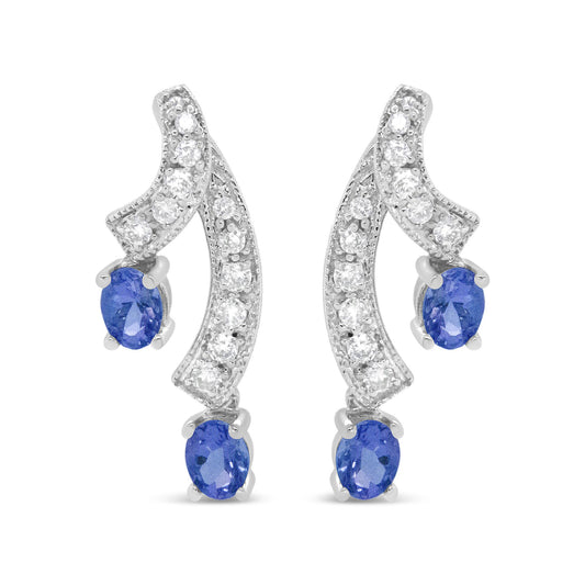 Pair of white metal earrings with curved design, prong-set with round white gemstones along the curves and blue oval gemstones at the ends, shown in a front-facing view.