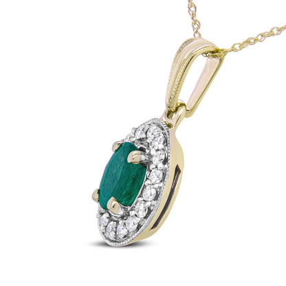 Yellow metal necklace pendant with an oval green gemstone center surrounded by small round white gemstones, shown in a close-up angled side view.