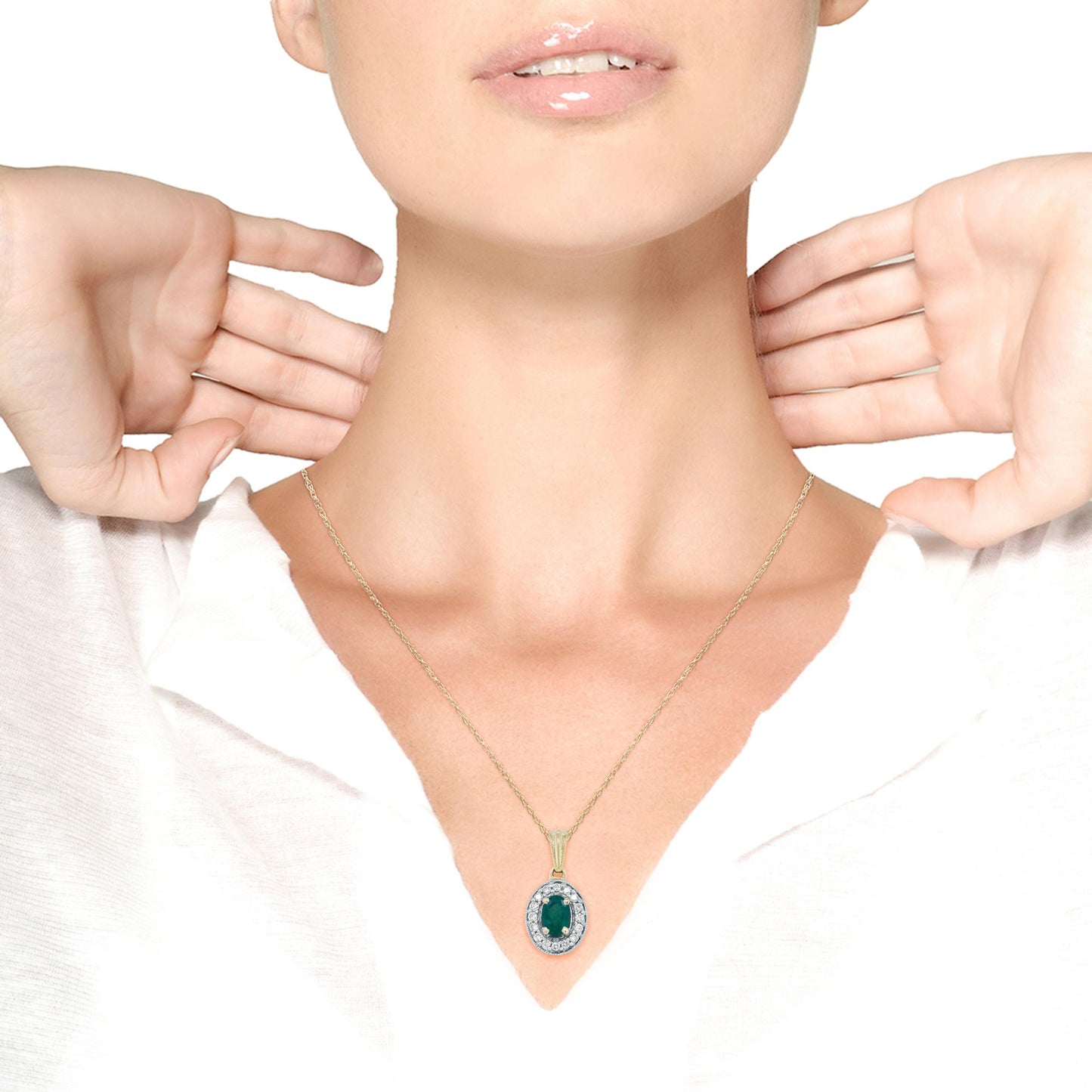 Necklace with an oval green gemstone surrounded by round white gemstones, set in yellow metal, worn by a model shown from the neck to mid-chest, front angle.