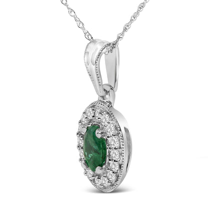 Close-up front angle of a white necklace pendant featuring an oval green gemstone center surrounded by round white gemstones in prong settings.