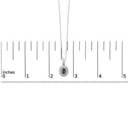 Necklace with an oval green gemstone pendant surrounded by round white gemstones, shown on a scale from a front angle.