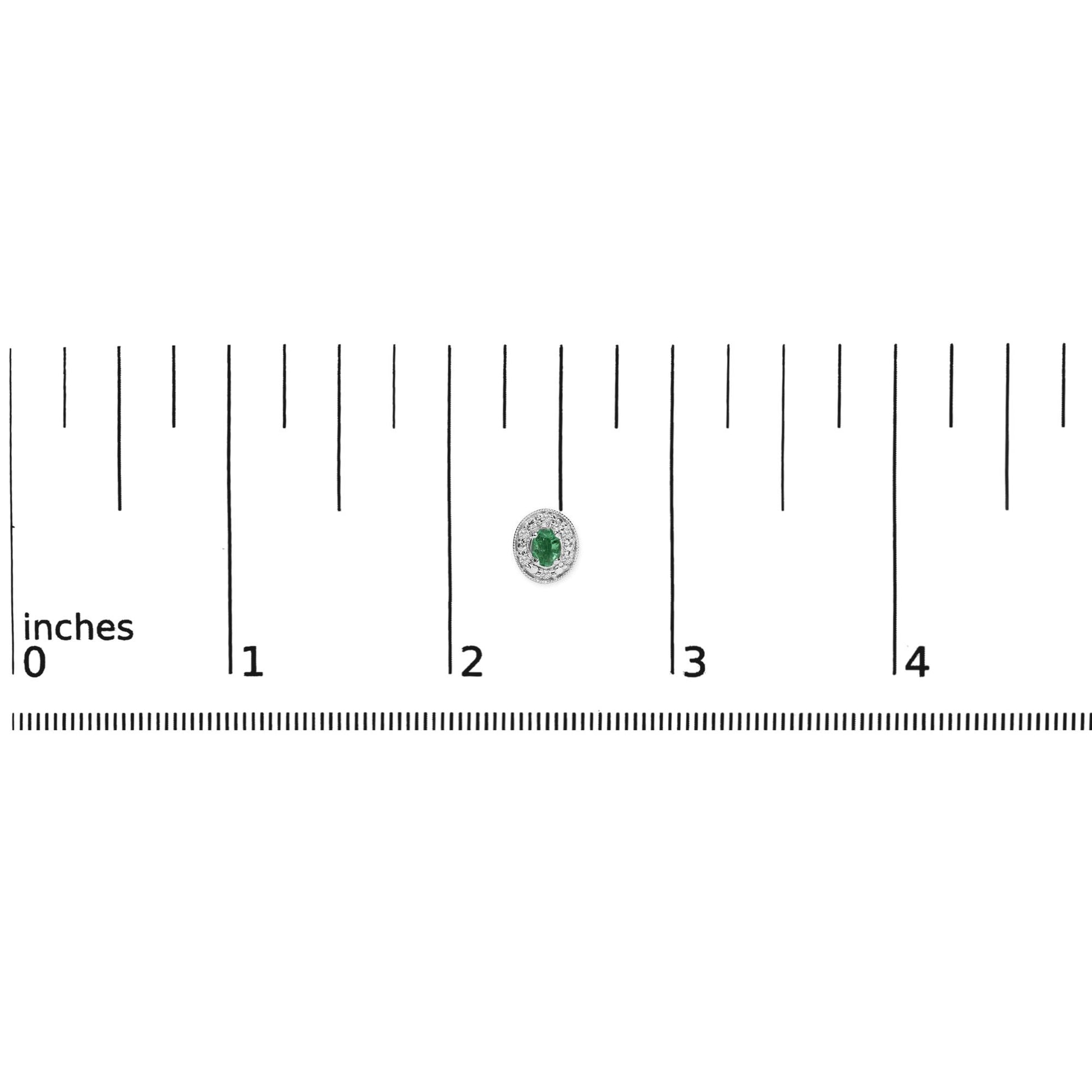 White earring with an oval green gemstone center surrounded by a halo of small round white gemstones, shown on a ruler scale.