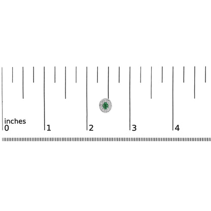 White earring with an oval green gemstone center surrounded by a halo of small round white gemstones, shown on a ruler scale.