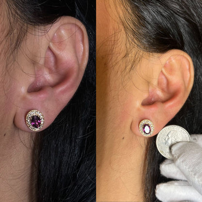 Close-up view of rose metal stud earrings worn on a model, featuring oval-shaped red and purple gemstones surrounded by round white gemstones in a prong setting; second image shows the earring next to a coin held by a gloved hand for size reference.