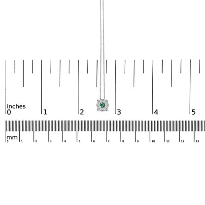 Front-facing close-up of a white necklace with a central round green gemstone surrounded by round white gemstones in a pave setting, displayed on a ruler for size reference.