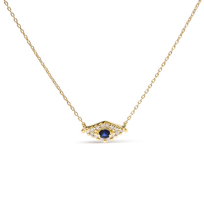 Front view of a yellow metal necklace with a central round blue gemstone surrounded by small round white gemstones in a pave setting.