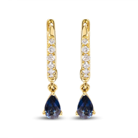 Front-facing shot of yellow metal earrings with a row of white round pave-set gemstones on the hoop and a dangling pear-shaped blue gemstone at the bottom.