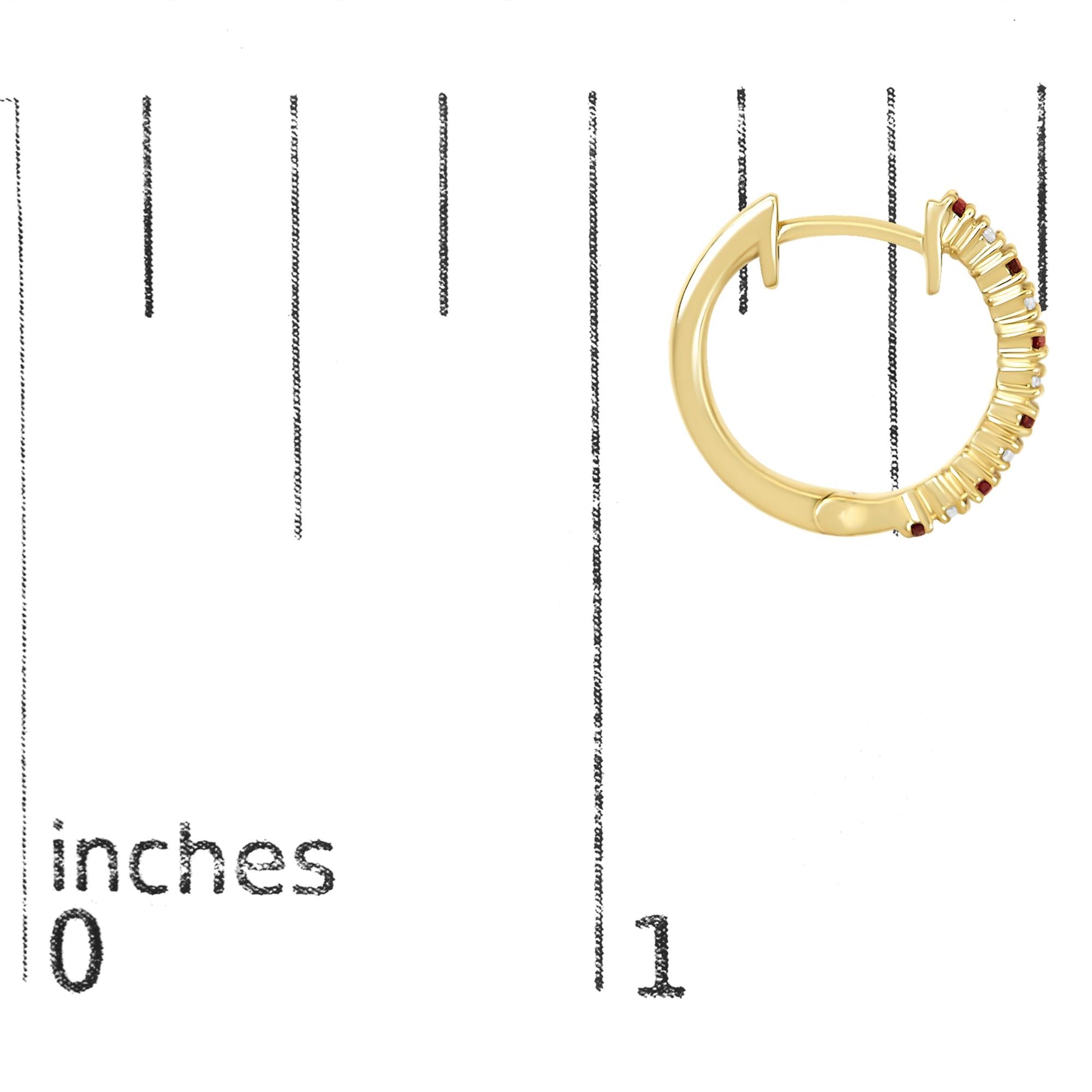 Yellow metal hoop earring with prong-set round white and red gemstones, shown on a scale with inch markings, side angle view.
