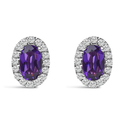 Front view of white metal earrings with oval purple gemstones in four-prong settings, surrounded by a halo of round white gemstones in a pave setting.
