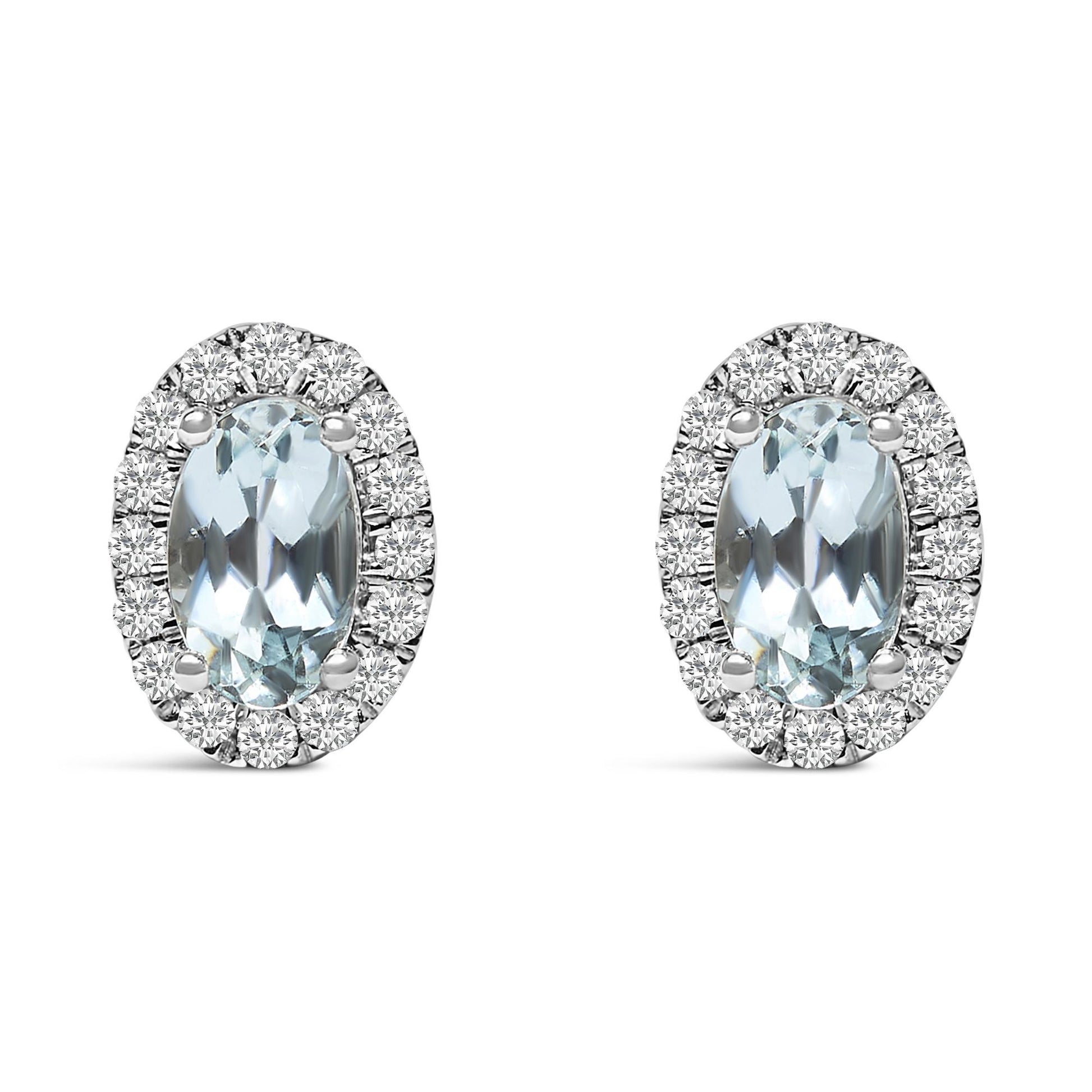 Front view of a pair of white metal oval earrings with a central blue oval gemstone surrounded by round white gemstones in a pave setting.