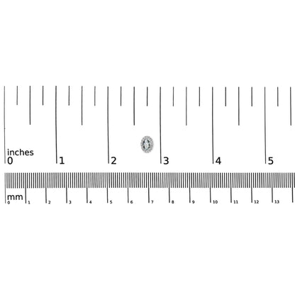 Close-up, top-down view of a single white earring with a blue oval gemstone surrounded by small white gemstones in a pave setting, placed on a ruler for size reference.