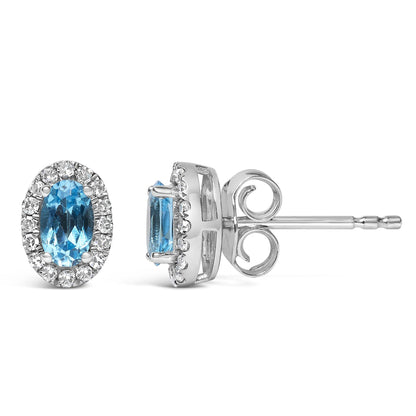 Pair of white metal stud earrings with oval blue gemstones surrounded by pave-set round white gemstones, shown from front and side angle.