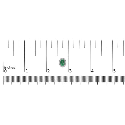 Close-up top-down view of a white earring with an oval green gemstone surrounded by small round white gemstones, placed on a ruler for size reference.