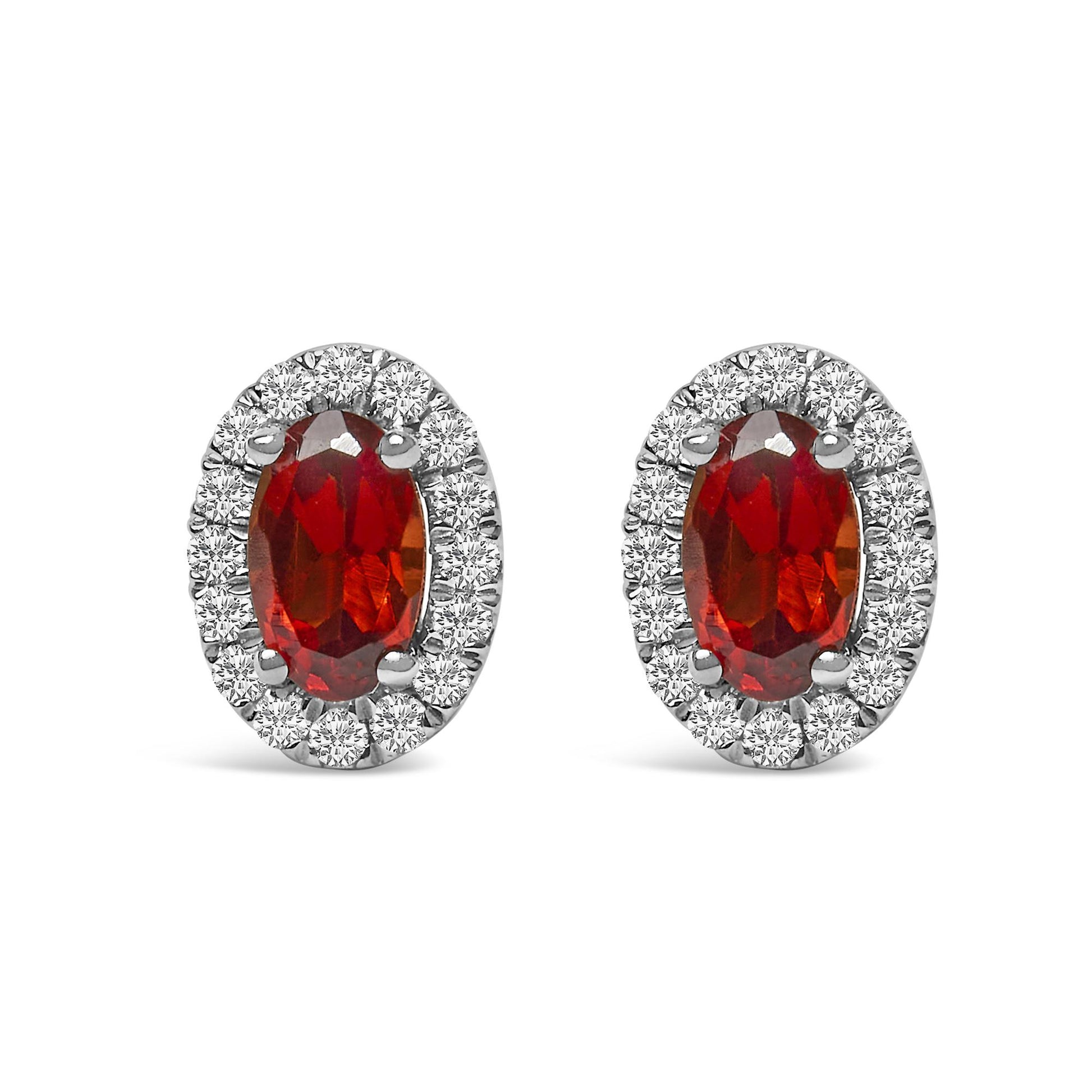 Front view of white metal oval earrings featuring a red oval gemstone center surrounded by a halo of small round white gemstones in pave setting.