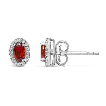 Pair of white metal earrings with oval red gemstones surrounded by round white gemstones, shown from front and side angles.