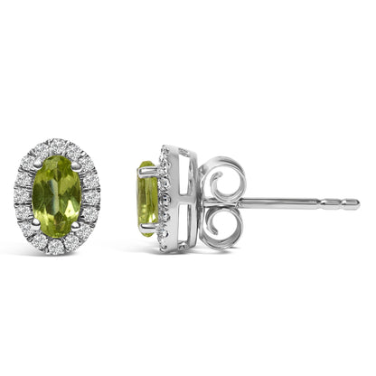 White metal stud earrings with oval green gemstones in four-prong settings, surrounded by a halo of round white gemstones in pave settings, shown from front and side angles on a white background.