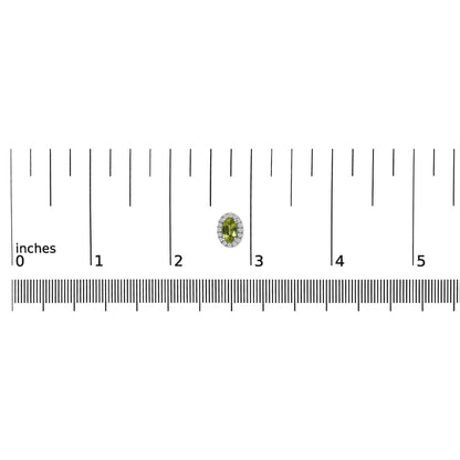 Single white metal earring with an oval green gemstone surrounded by small round white gemstones in a pave setting, shown on a ruler for size reference from a top-down angle.