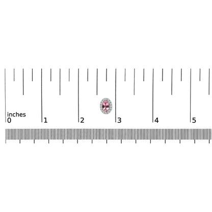 Close-up of a white metal oval-shaped earring with a pink gemstone center surrounded by small round white gemstones, shown on a ruler for size reference.