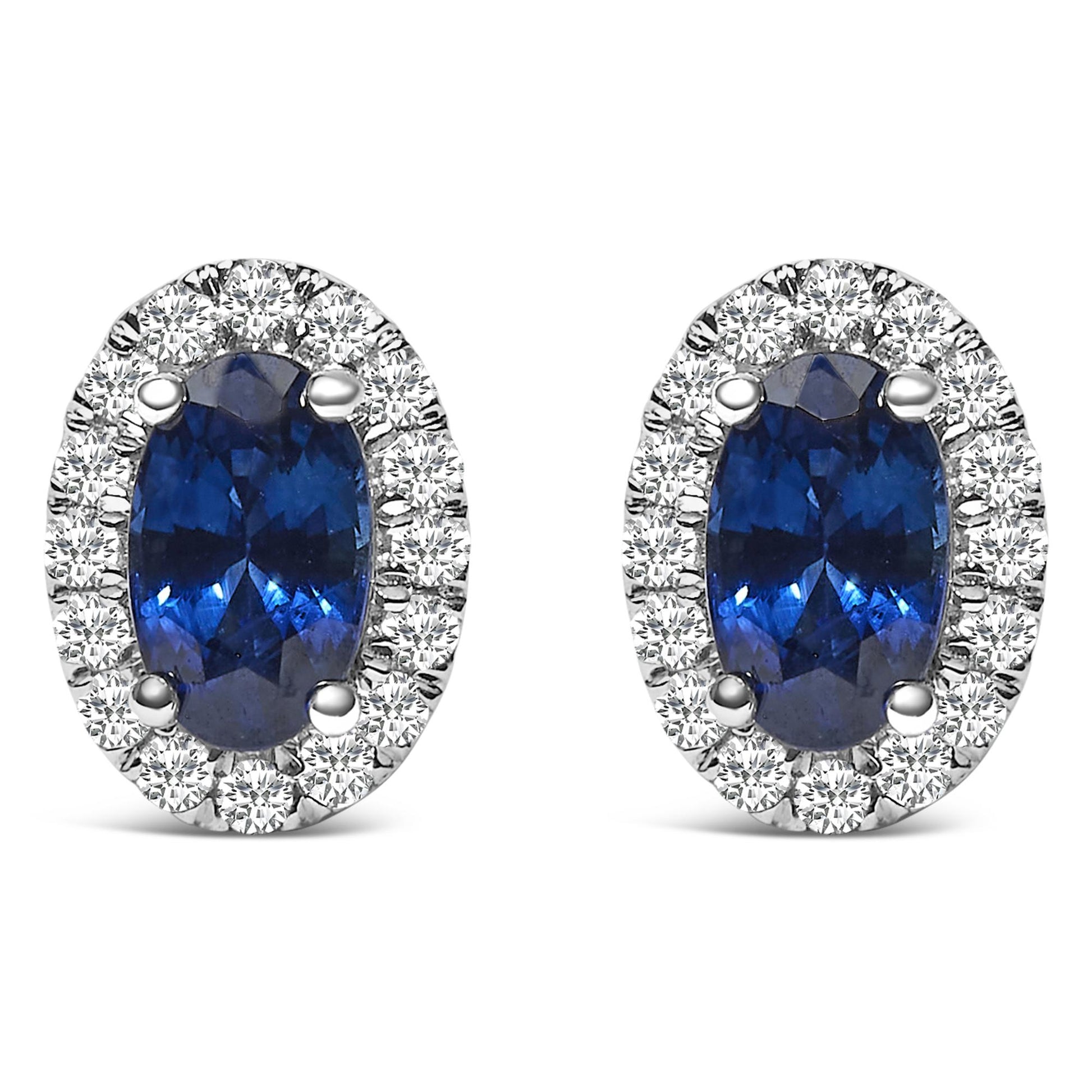 Front view of white metal oval earrings featuring blue oval gemstones surrounded by small round white gemstones in pave setting.