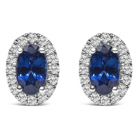 Front view of white metal oval earrings featuring blue oval gemstones surrounded by small round white gemstones in pave setting.