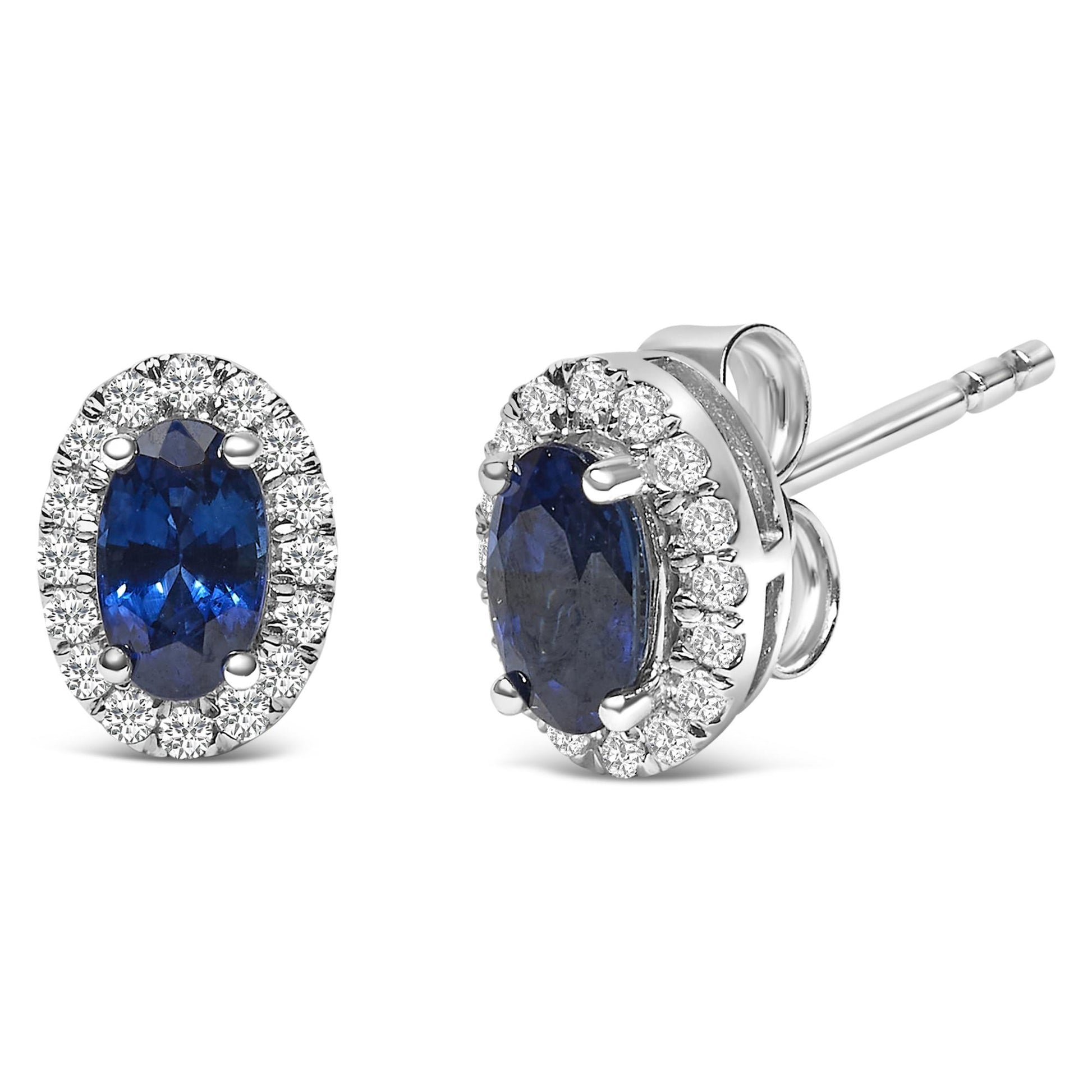 Close-up front and side view of white metal stud earrings featuring oval blue gemstones with a halo of round white gemstones in a pave setting.