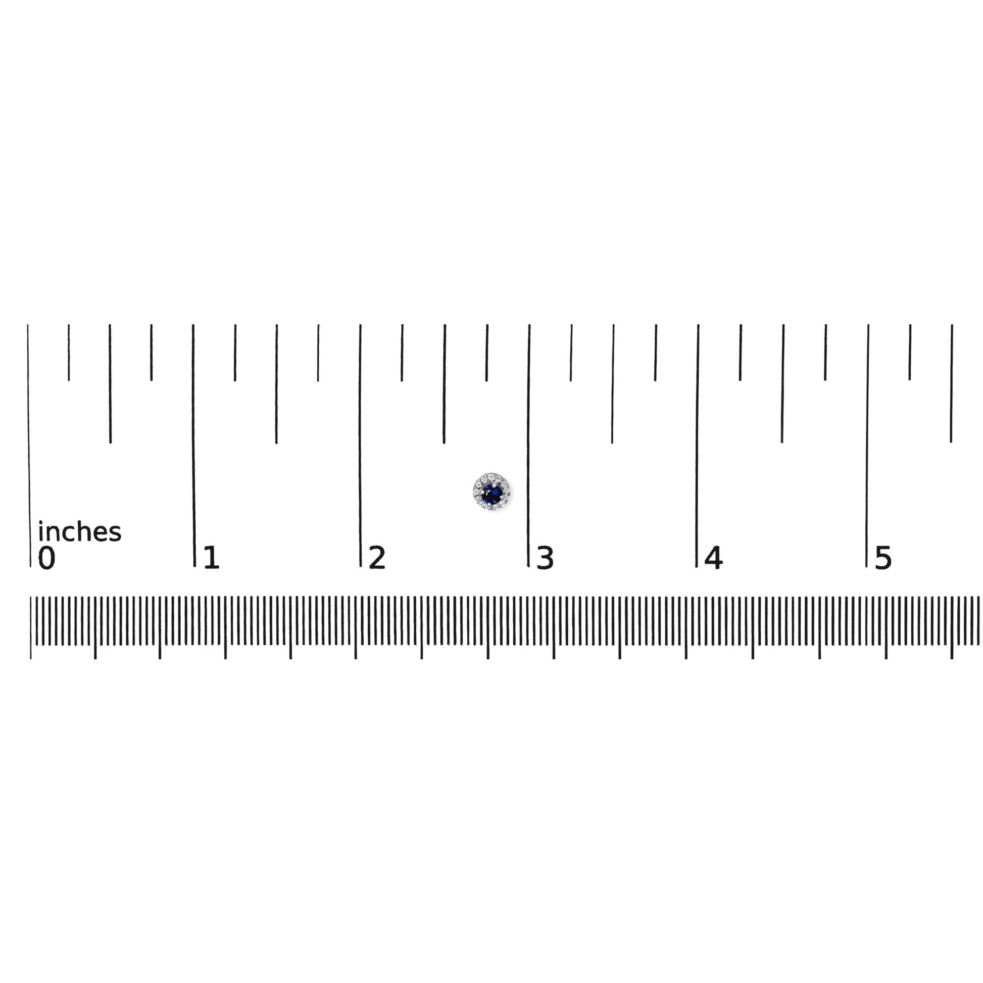 Close-up front view of white metal round stud earring with a blue gemstone center surrounded by small white gemstones, placed on a ruler for size reference.