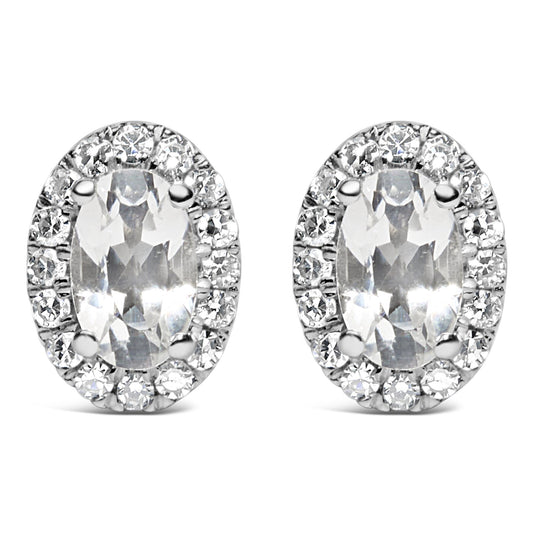 Front angle view of white metal oval-shaped stud earrings with central oval white gemstones in four-prong settings, surrounded by a pave setting of round white gemstones.