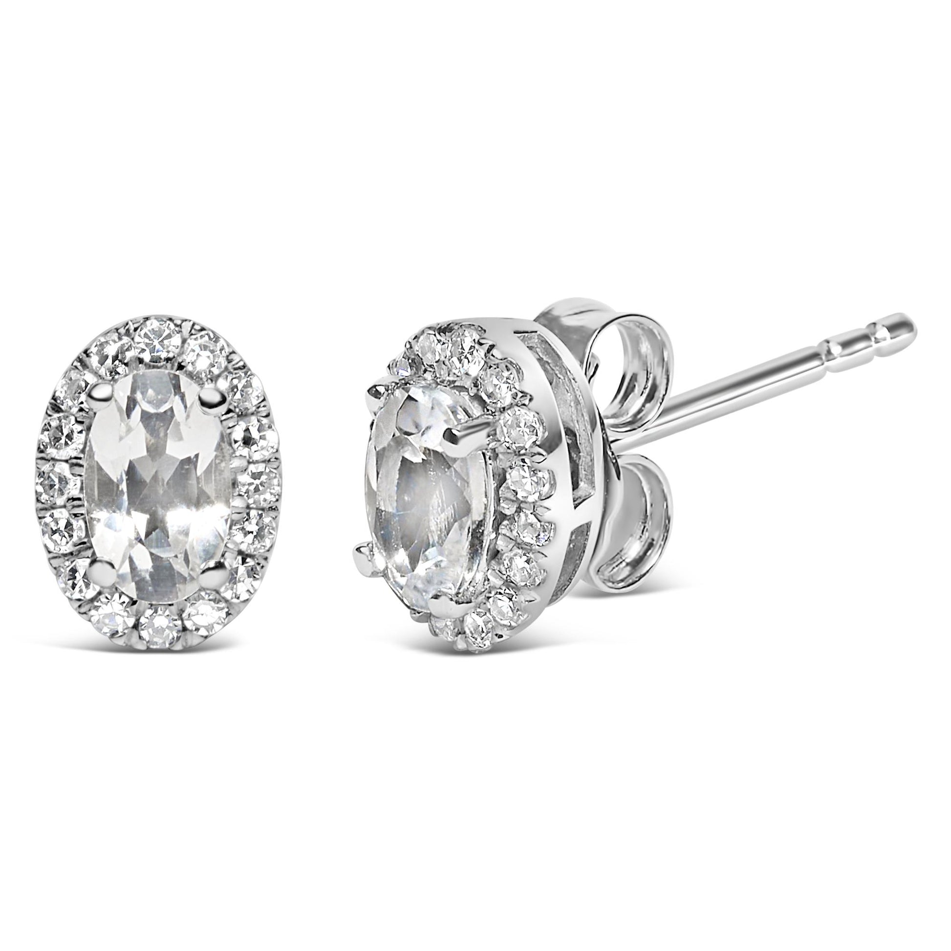 Pair of white metal stud earrings with oval white gemstones surrounded by a halo of round white gemstones, shown in a front and side angled view.