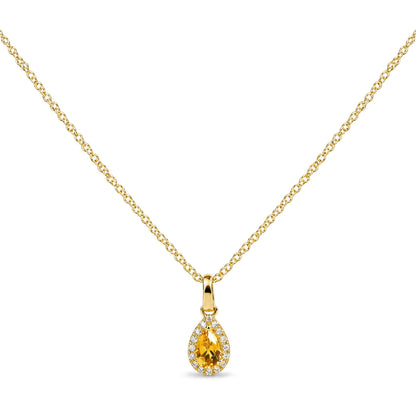 Close-up front view of a yellow metal necklace with a pear-shaped yellow gemstone pendant surrounded by round white gemstones in prong settings.