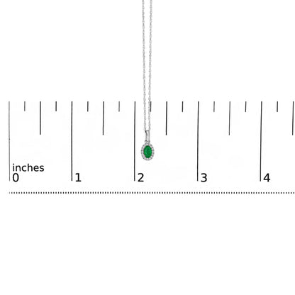 White metal necklace with a pendant featuring an oval green gemstone surrounded by small white gemstones in a micro-pave setting, photographed against a ruler for size reference.