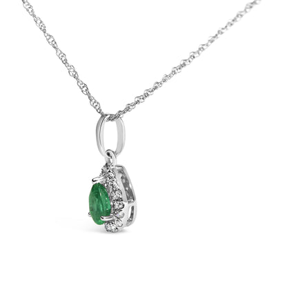 Close-up side angle of a white metal necklace with a pear-shaped green gemstone pendant surrounded by small white gemstones in a micro-pave setting.