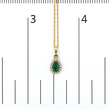 Close-up front view of a yellow metal necklace pendant featuring a pear-shaped green gemstone surrounded by round white gemstones in a prong setting, shown on a scale.