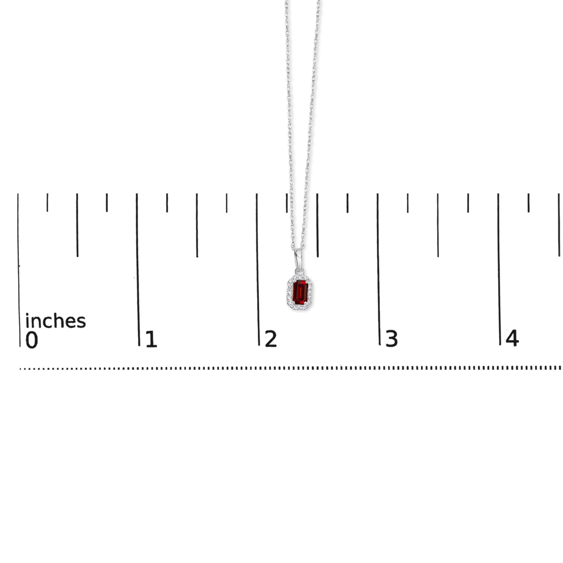 White metal necklace with a rectangular red gemstone pendant surrounded by small white gemstones in a micro-pave setting, shown hanging vertically against a ruler for size reference.