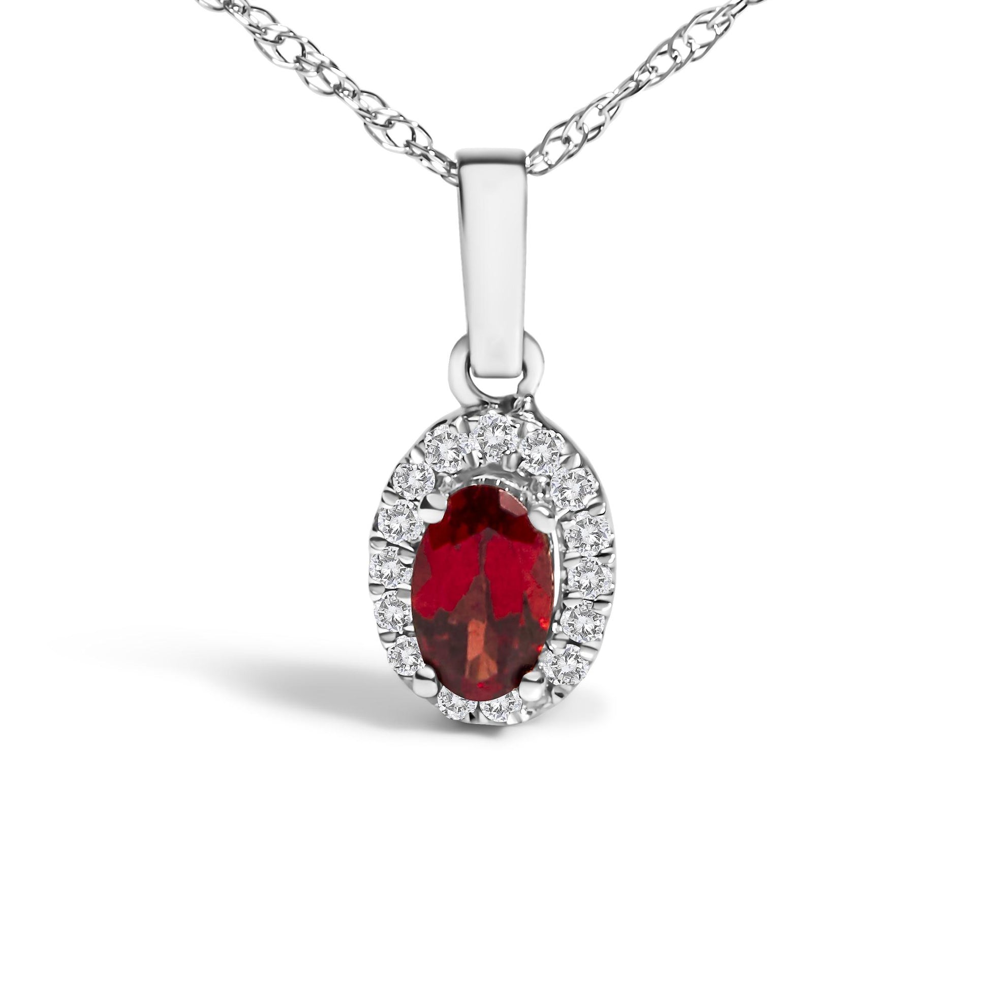Close-up front-facing view of a white metal necklace with an oval red gemstone pendant surrounded by small round white gemstones in a micro-pave setting.