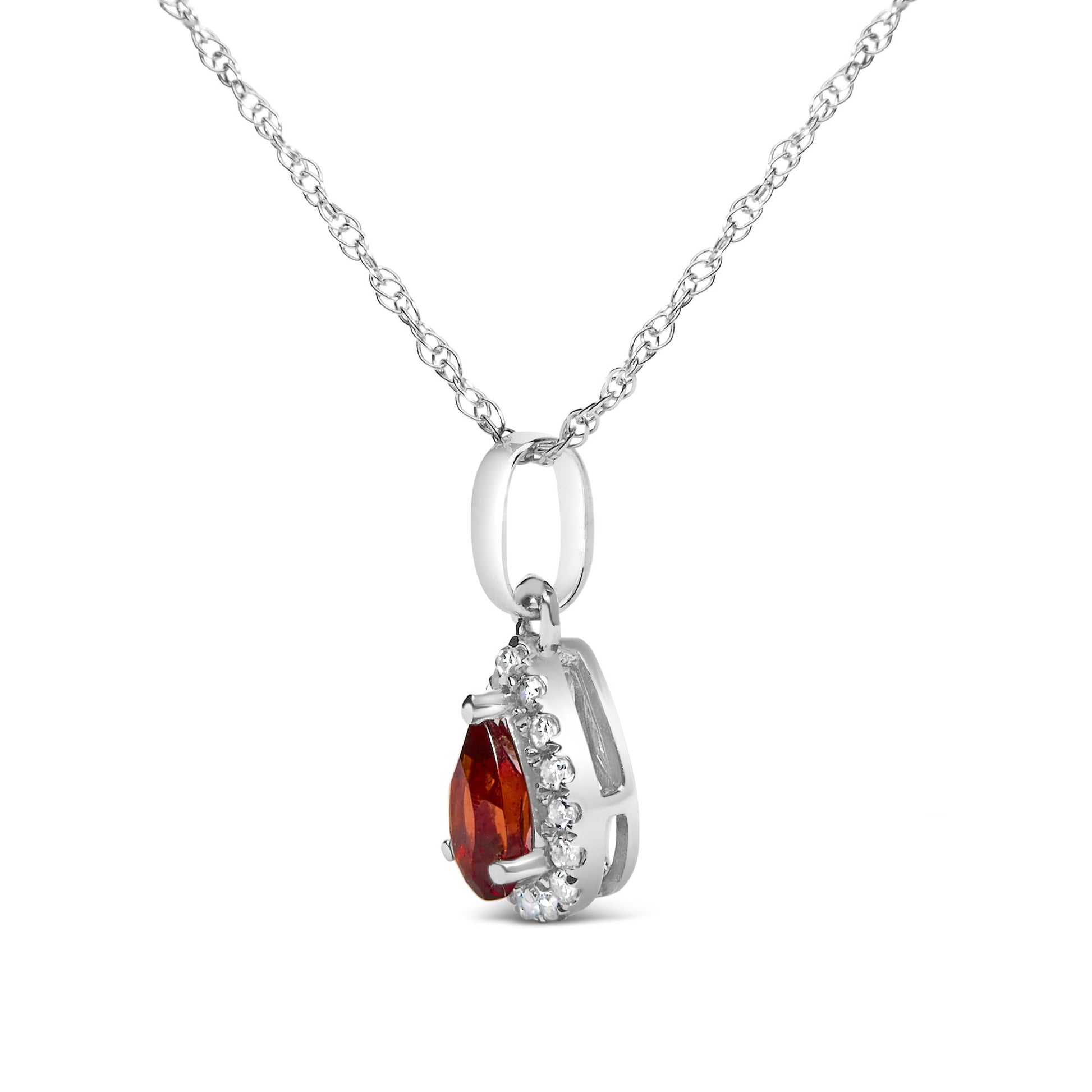Close-up side angle of white metal necklace with pear-shaped red gemstone pendant surrounded by small round white gemstones in micro-pave setting.