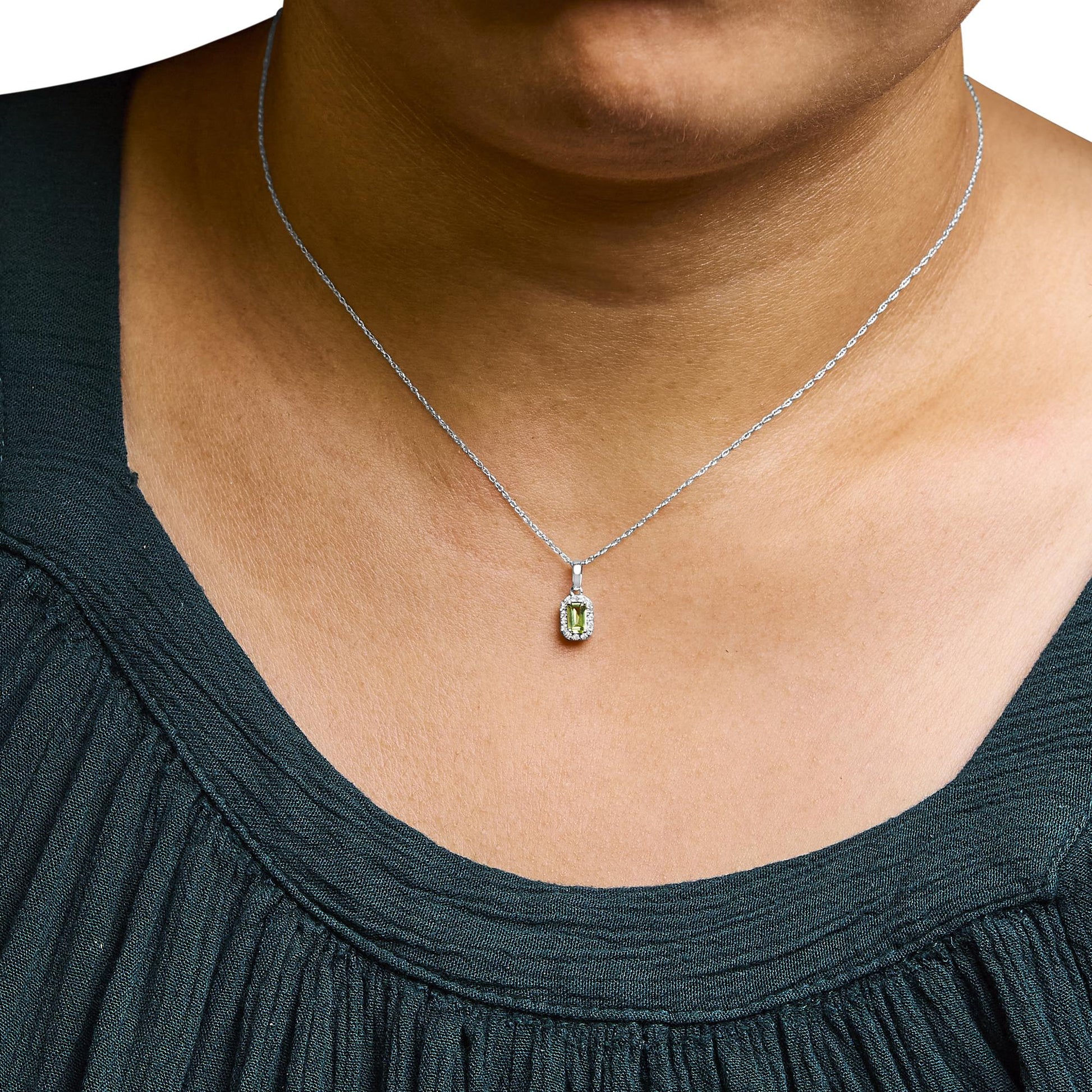 White necklace with a yellow emerald-shaped gemstone pendant surrounded by small round white gemstones, worn on a model, front angle.