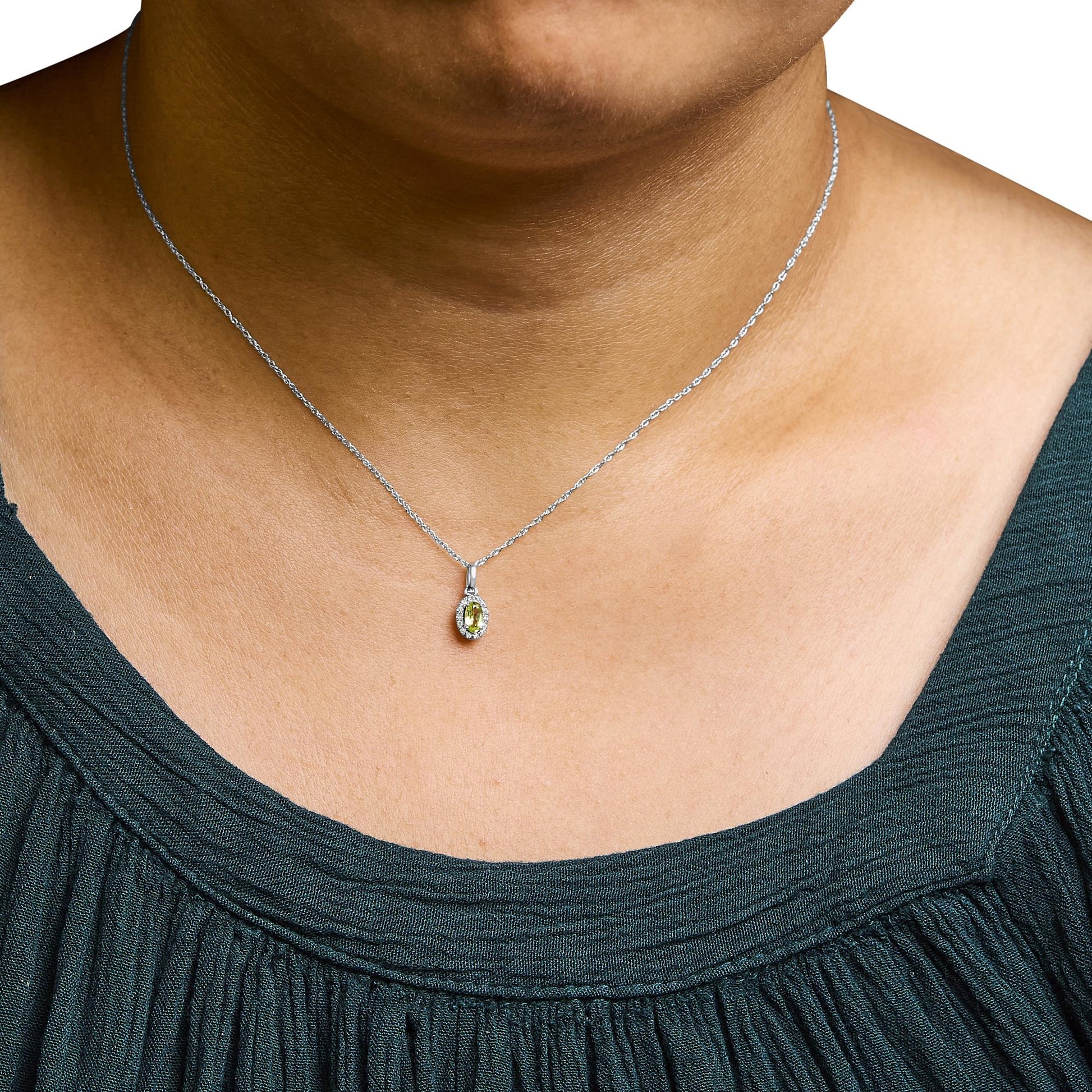 Close-up front view of white metal necklace on a model, featuring a pendant with a yellow oval gemstone surrounded by small white round gemstones in a micro-pave setting.
