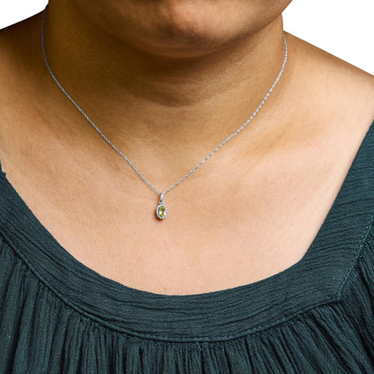 Close-up front view of white metal necklace on a model, featuring a pendant with a yellow oval gemstone surrounded by small white round gemstones in a micro-pave setting.
