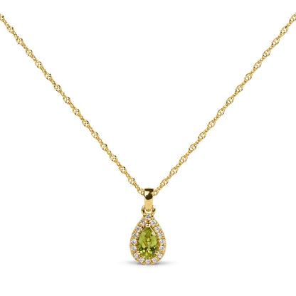 Close-up front view of a yellow metal necklace with a pear-shaped green gemstone pendant surrounded by small round white gemstones in prong settings.