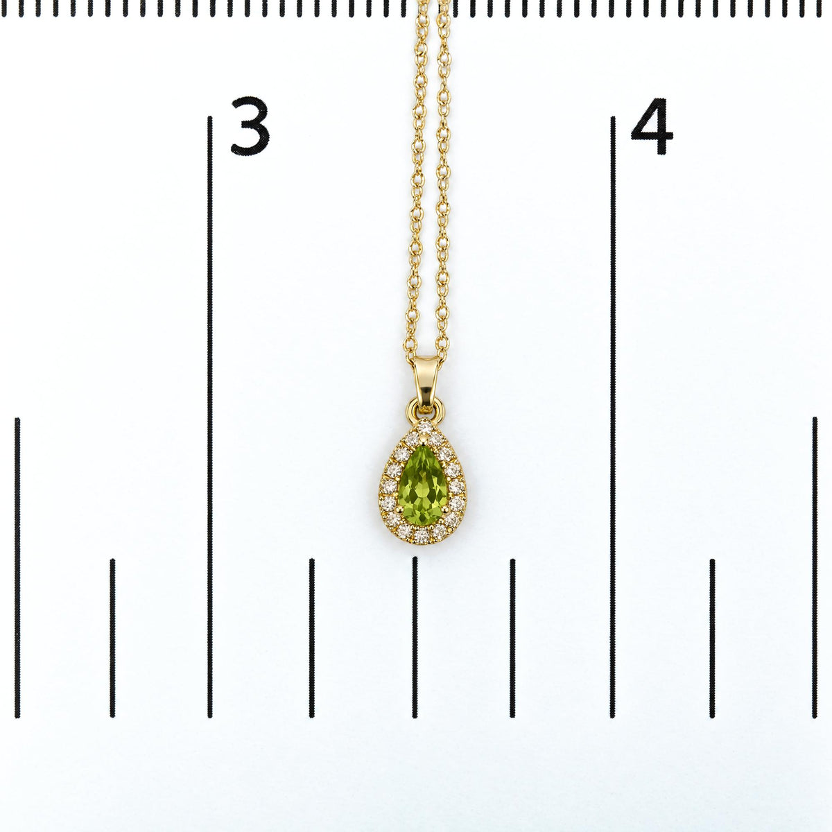Close-up front view of a yellow necklace with a pear-shaped green gemstone pendant surrounded by round white gemstones, shown on a measurement scale.