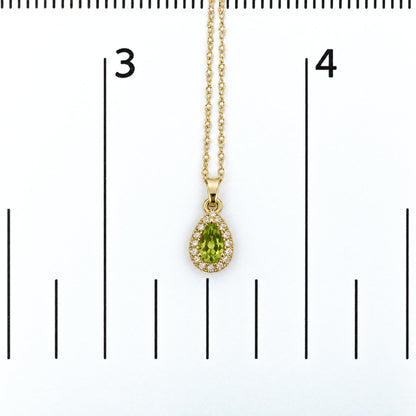 Close-up front view of a yellow necklace with a pear-shaped green gemstone pendant surrounded by round white gemstones, shown on a measurement scale.