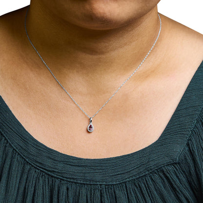 Close-up front view of a white metal necklace on a model, featuring a pendant with a pink emerald-shaped gemstone surrounded by small white round gemstones in micro-pave setting.