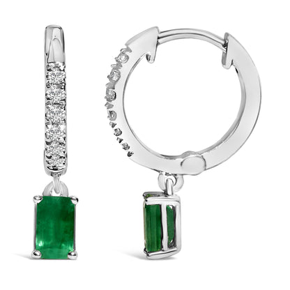 Close-up front and side views of white metal hoop earrings with round white gemstones pave set along the front curve and a rectangular green gemstone dangling from each hoop.