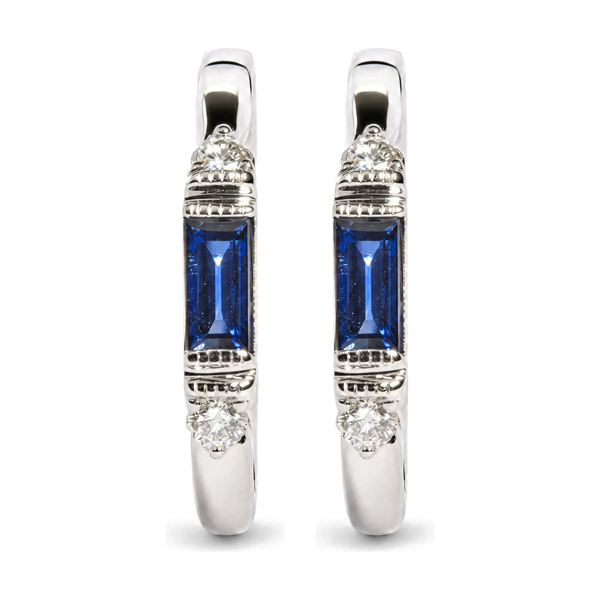 Close-up front view of a pair of white metal earrings featuring a round white gemstone in prong settings near the top and bottom, and a blue baguette-shaped gemstone in a channel setting in the center, shown on a white background.