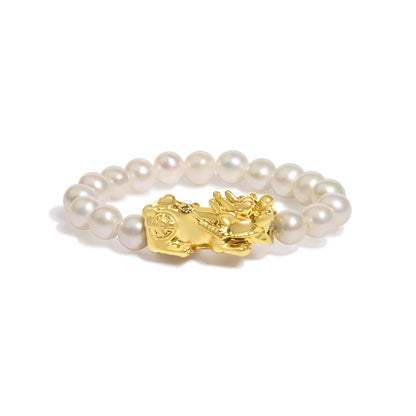 Close-up front angle of a yellow metal ring with a floral design centerpiece, surrounded by a string of white pearls.