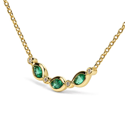 Close-up front angle of a yellow necklace with interconnected links featuring a curving centerpiece adorned with bezel-set round white gemstones and marquise-shaped green gemstones.